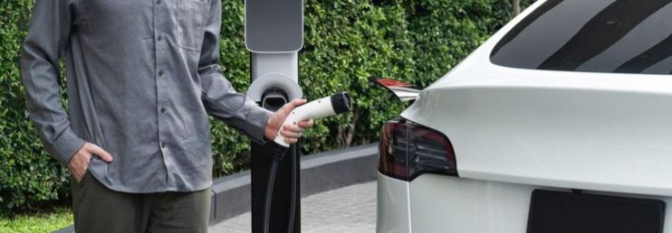 Young man with EV electric car in green sustainable city innards