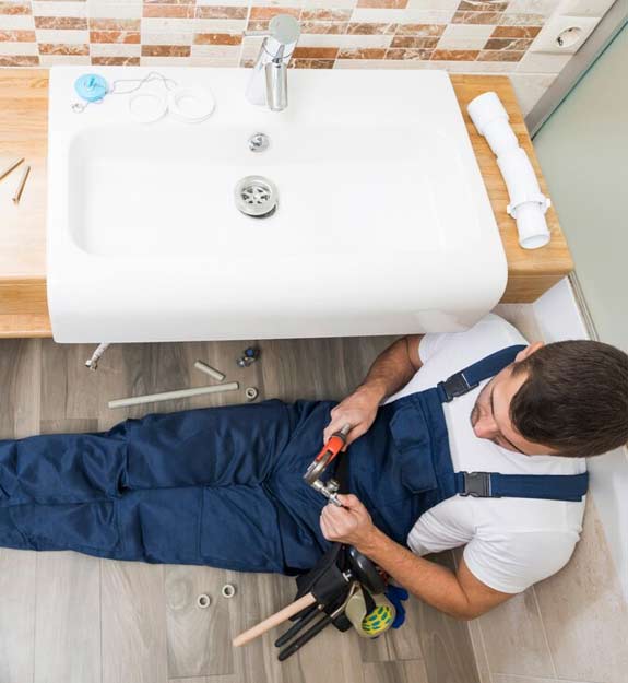 Plumber sitting in bathroom and fitting bathtub